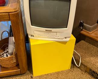 Vintage television on a stand with a yellow storage cube