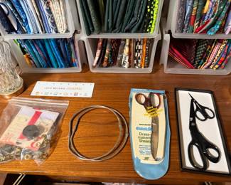 Embroidery scissors, hoop and notions with fabric racks behind