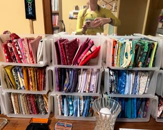Bins of folded quilting cotton in reds, greens and florals