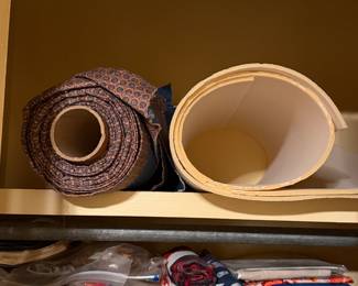 Rolled batting and a wooden quilting hoop on a shelf