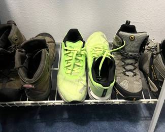 Selection of men's athletic footwear on a shoe rack, including Keen hiking boots, bright yellow Puma running shoes, and Merrell hiking boots.