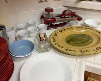 Dinnerware galore: white plates, red chargers, bowls, mugs and a hand painted platter.