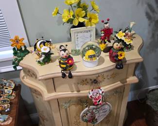 Painted cream accent cabinet with bumblebee figurines and flowers