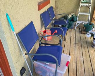 Patio with blue sling chairs, bins and folding step ladder