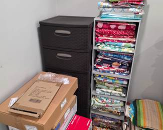 Fabric bolts on rolling shelf with plastic drawer unit and boxed items