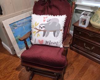 Burgundy upholstered glider rocker with sloth pillow