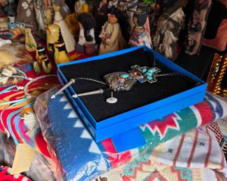 Turquoise-style bolo tie in box with Native American-style figures