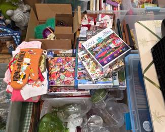 Clear bins of jigsaw puzzles, books and glassware