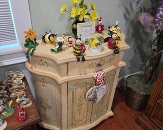 Painted cream accent cabinet with bumblebee figurines and flowers