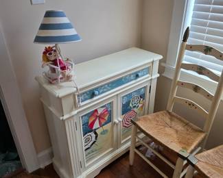Painted cream console cabinet with striped lamp and ladder-back chair