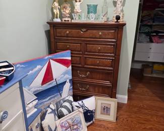 Wood chest of drawers with angel figurines, lamp and beach-themed art
