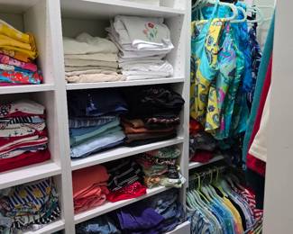 Closet shelves of women's folded tops and tropical print blouses