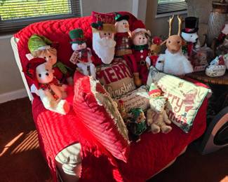 Christmas plush Santas, snowmen and elves on red-covered recliner