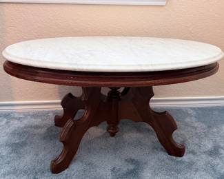 Oval Vintage marble-top accent table with ornate carved wooden pedestal base and curved legs.