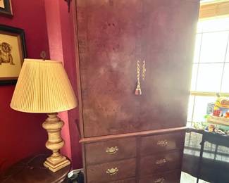 Vintage wooden TV armoire with ornate crown molding, double doors, six storage drawers, and interior swivel TV stand.