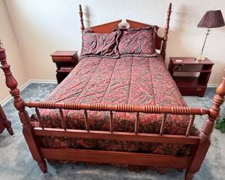 Vintage wooden four-poster bed with spindle headboard and footboard, matching nightstands, and patterned bedding.