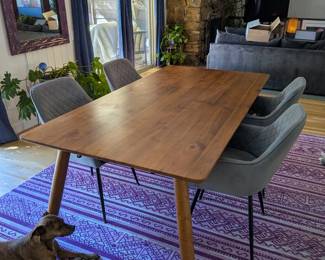 Mid-century modern walnut-tone dining table with tapered legs, plus 6 gray velvet quilted dining chairs (Alpha Company). Purple boho area rug. Purple framed mirror. Navy blue velvet curtains.
