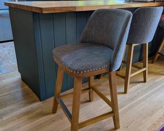 Gray upholstered swivel counter stools with nailhead trim and wood legs, set of 3.