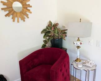 Wood starburst sunburst mirror. Pink Chinese evergreen (aglaonema) plant in black pot. Marble top quatrefoil side table with chrome base. Gray faux fur rug.