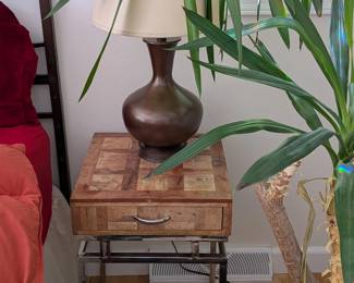 Wood parquet nightstand with drawer and chrome base, mid-century modern style. Gray shag rug.