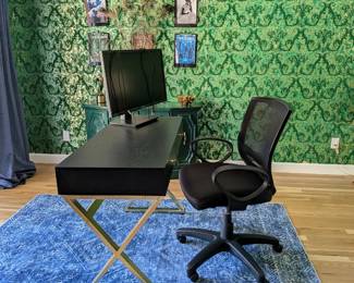 Black desk with gold brass X-legs, mid-century modern style. Black mesh office chair. Asus 30" adjustable monitor (HDMI). Blue boho area rug.