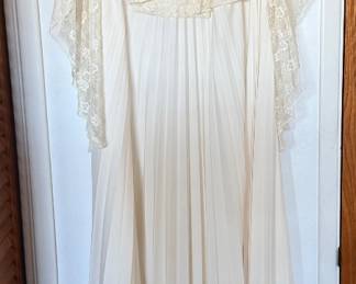  1970s maxi dress featuring an off-the-shoulder or scoop neckline with a floral lace capelet/flutter overlay and an accordion-pleated skirt