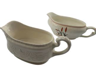 290 - 2 Vintage Gravy Pitchers (Description): One features an embossed decorative pattern while the other displays a painted cattail design with red trim.