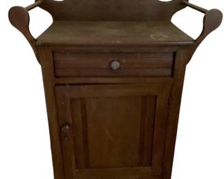 714 - Vintage Washstand w/ Towel Bar Sides (Description): Mahogany washstand featuring a scalloped backsplash with towel bar arms, one drawer with knob pull, and a single cabinet door with reeded panel detail. Measures 33 inches high by 28 inches wide by 14 inches deep.