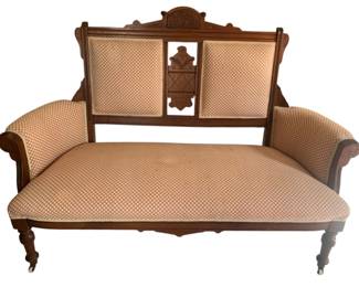 350 - Walnut Victorian Carved Settee (Description): Victorian sofa featuring upholstery with an elegant diamond pattern fabric. The piece showcases ornate carved wooden details on the backrest, arms, and frame characteristic of Victorian craftsmanship. The sofa rests on turned wooden legs with casters for mobility. Measures 42 inches high by 58 inches wide by 23 inches deep.