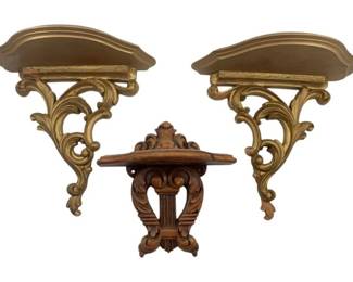 799 - 3 Wall Shelves 9" (Description): Three decorative wall shelves measuring 9 inches. The lot includes two matching gold-toned shelves with ornate scrolling Rococo-style brackets and one carved wood shelf with an elaborate lyre-form bracket design.