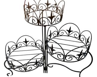 1007 - 3 Tier Metal Planter 22"x20" (Description): Three tier metal planter featuring decorative scrollwork and fleur-de-lis motifs throughout. The stand includes one elevated basket and two lower baskets arranged at different heights for displaying plants. Measures 22 inches by 20 inches.