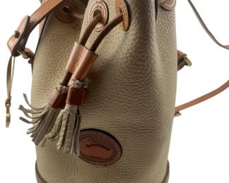 798 - Dooney & Bourke Handbag 9.5"x6.25" (Description): Dooney & Bourke handbag in a bucket style with pebbled leather body and smooth leather trim. Features the signature duck logo patch, drawstring closure with leather tassels, and adjustable shoulder strap. Measures 9 1/2" x 6.25".
