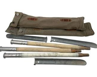 664 - WWII Tent Stakes w/ Canvas Carrying Case 17" (Description): A set of WWII-era tent stakes with a canvas carrying case. The stakes feature shafts with metal ferrules and tips, accompanied by metal sheaths. The canvas bag has reinforcement tabs and button closures, with faint markings visible.