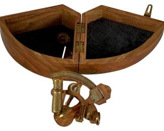 1056 - Sextant w/ Box 3"x7"x5" (Description): A brass sextant accompanied by its fitted wooden storage box. The sextant features traditional brass construction with telescope attachment. Measures 3 inches by 7 inches by 5 inches.