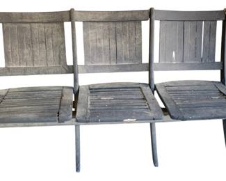 1009 - 3 Seat Painted Black Folding Seat Bench (Description): A three-seat painted black bench with a slatted design. The bench features folding seats and a sturdy wooden construction. Measures 32 inches high by 55 inches wide by 24 inches deep.