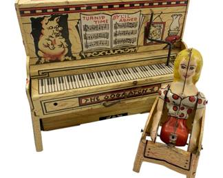 787 - Lil Abner Toy (Not Complete) 6"x7"x4" (Description): Lil Abner toy, not complete. This vintage lithographed tin toy features the Dogpatch theme with Daisy Mae figure and upright piano decorated with 'Turnip Time by Lil Abner' sheet music and pig imagery. Measures 6 inches by 7 inches by 4 inches.