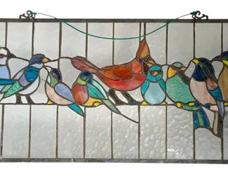 1054 - Stained Glass Bird Hanger 24"x13.5" (Description): Stained glass bird hanger featuring colorful birds perched on a branch. The panel is set in a metal frame with decorative corner brackets and hanging wire. Measures 24" x 13.5".