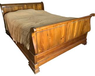 704 - Queen Sleigh Bed 44"x66"x93" (Description): Queen sleigh bed crafted in warm-toned wood with classic rolled headboard and footboard design. Features paneled construction on both ends with attractive wood grain visible throughout. Measures 44 inches in height by 66 inches in width by 93 inches in length.