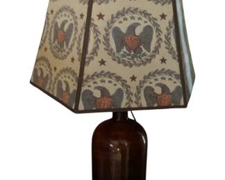 735 - Amber Bottle Lamp 26" (Description): Amber bottle lamp measuring 26 inches in height. The lamp features a brown glass bottle base converted into a functional lighting piece, topped with a decorative shade.