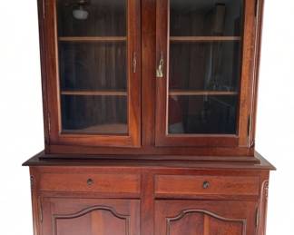 336 - French 2 Part Bookcase 94"x62"x21" (Description): Two-piece bookcase featuring an upper section with glass-paneled doors and interior shelving, and a lower section with two drawers and two cabinet doors. The piece displays carved detailing on the arched crest and decorative panel work on the cabinet doors. Measures 94 inches tall by 62 inches wide by 21 inches deep.