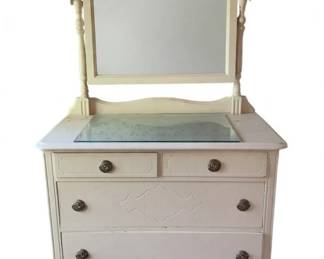 750 - Painted White Dresser w/ Mirror 68"x38"x19" (Description): Painted white dresser with tilting mirror. The dresser features two small drawers over two larger drawers with decorative carved panel details and round metal drawer pulls. Includes a glass top protector. Supported on turned legs with casters. Mirror is mounted on turned spindle posts. Measures 68 inches tall by 38 inches wide by 19 inches deep.