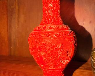 Asian-Style Carved Red Vase – Decorative red vase displayed on a wooden stand.