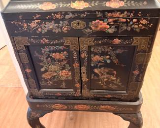 Asian Black Lacquer Jewelry Cabinet – Beautiful black lacquer cabinet with hand-painted floral and bird designs, multiple drawers, and curved legs.