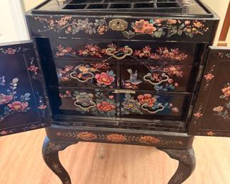 Asian Black Lacquer Jewelry Cabinet – Beautiful black lacquer cabinet with hand-painted floral and bird designs, multiple drawers, and curved legs.