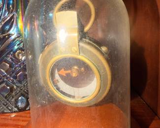 Vintage Brass Instrument Display – Small brass instrument or compass-style collectible displayed beneath a glass dome.