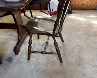 Vintage dark stained wooden Windsor-style dining chair paired with a matching trestle dining table displaying ceramic dishware.