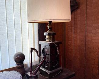 Vintage dark wood table lamp with brass accents and a tall drum shade, displayed alongside a decorative miniature wooden harp.