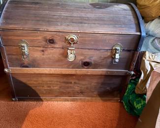 Vintage dome-top wooden steamer trunk with brass hardware and latches.