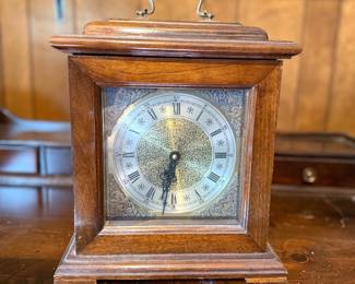 Vintage Crown bracket-style mantel clock featuring a dark wood case, brass carrying handle, and an ornate metal face with Roman numerals.