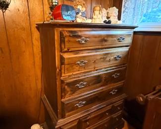 Rustic dark stain pine highboy chest of drawers with antique-style bale pulls, displayed alongside various decorative figurines.